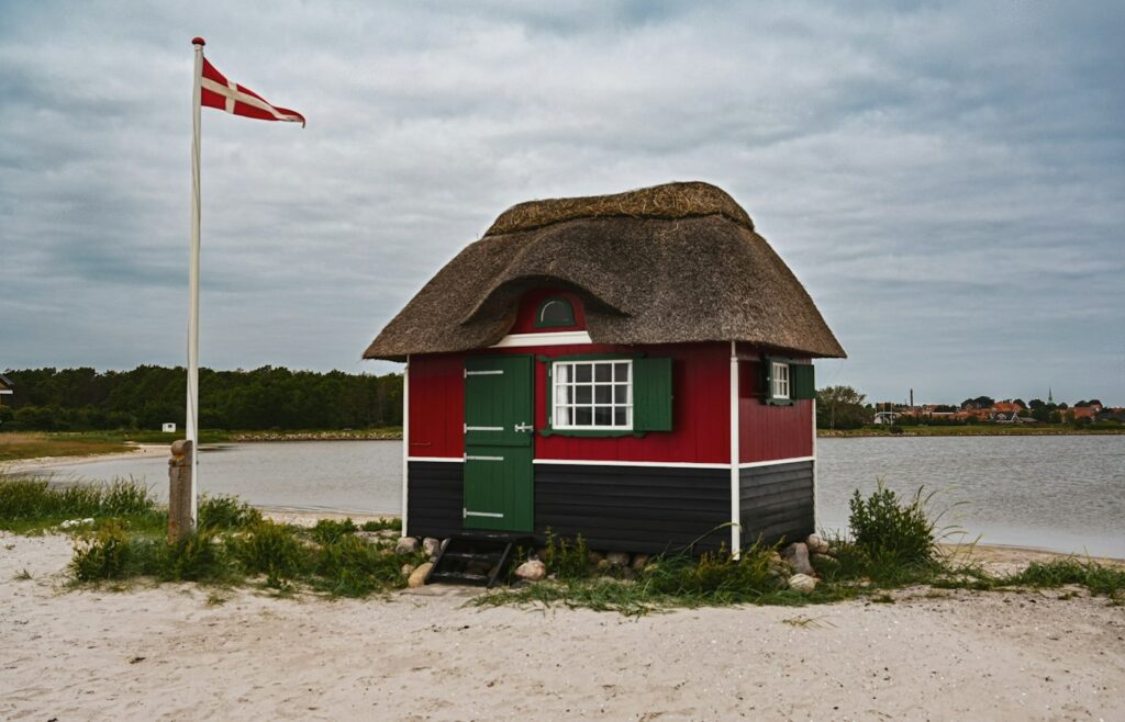 Rotes Reetdach-Strandhaus mit dänischer Flagge